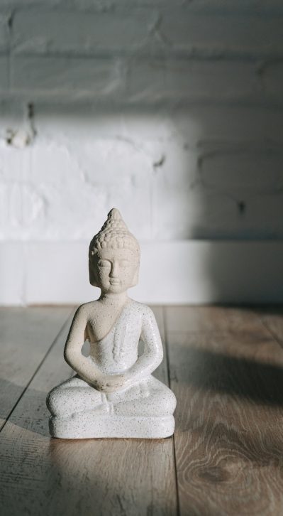 A White Buddha Figurine on Wooden Surface